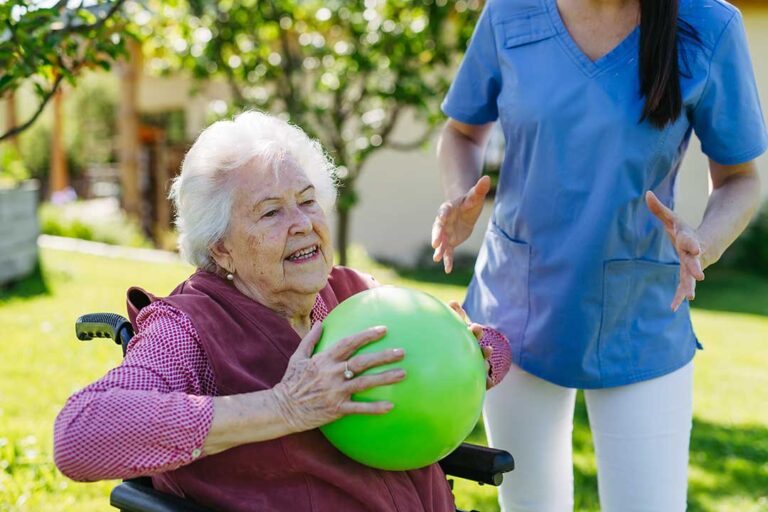Adult children and elderly parent sharing a conversation and laughter in a cozy assisted living community lounge.