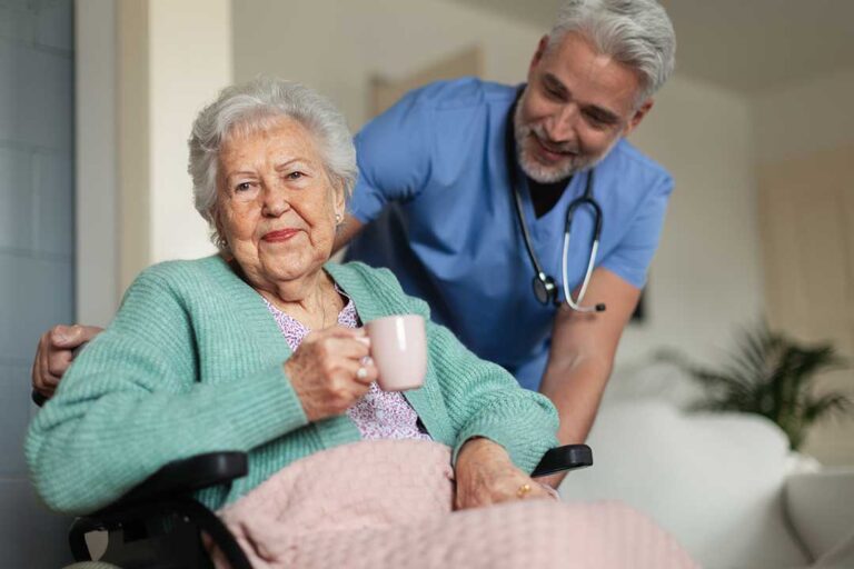 Resident and caregiver calmly discussing a concern at a table in a shared assisted living room.